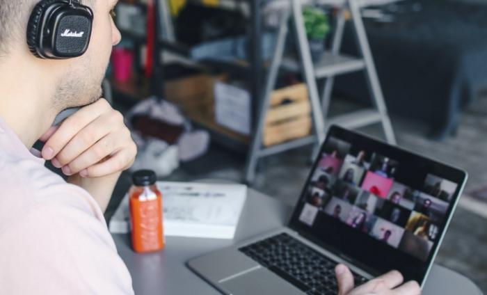 Photo of a man at a computer with headphones on attending a virtual class
